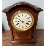 An Edwardian mahogany mantle clock with a domed top and pillars on brass ball feet with an