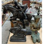 A large bronze model of a girl on a horse jumping a cross country fence together with another of a