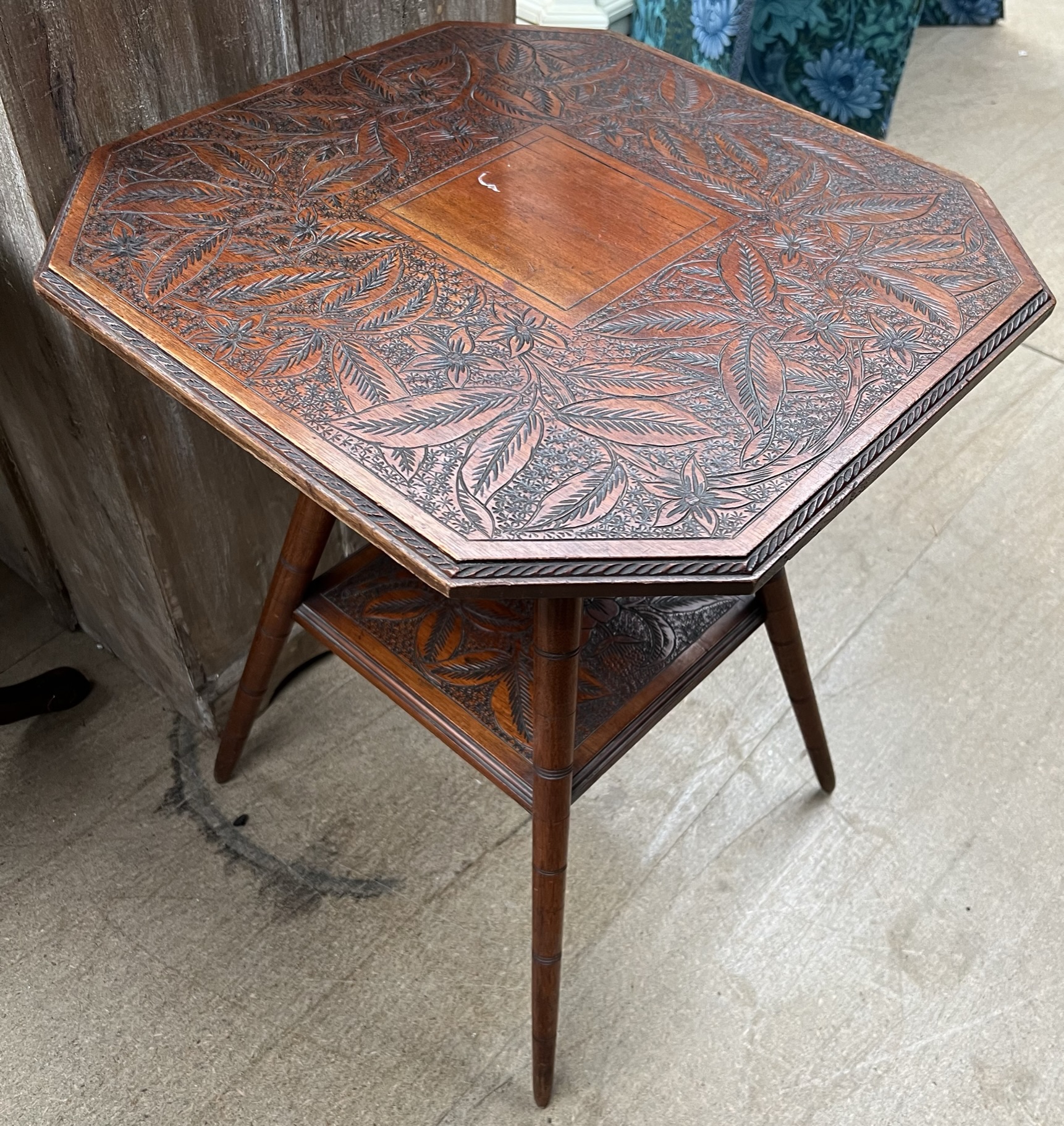 An Edwardian occasional table with a leaf carved square top and canted corners on four splayed legs
