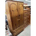 A tall pine chest of drawers together with a pine wardrobe