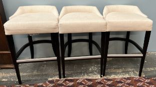 A set of three cream upholstered bar stools with ebonised square tapering legs