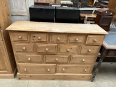 A modern pine chest with a rectangular top above an arrangement of fourteen drawers on a plinth