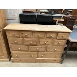 A modern pine chest with a rectangular top above an arrangement of fourteen drawers on a plinth