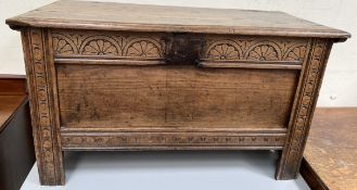 An 18th century oak coffer with a planked moulded top above a fan carved frieze and panelled body