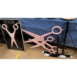 A barber shop furniture double sided "Hair Salon" sign mounted with pink scissors together with two