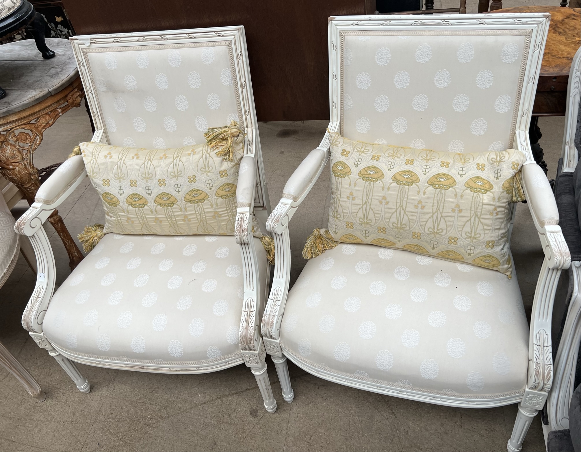 A pair of continental cream painted upholstered elbow chairs with pad upholstered back,