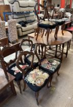 A set of six Victorian walnut balloon back dining chairs with floral and bead carved hoop back