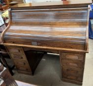 An early 20th century serpentine tambour fronted desk with twin pillars on plinths