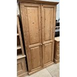A pine side cabinet with a pair of four panelled doors