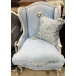 A continental cream painted upholstered wing back chair with pad upholstery and a squab seat on