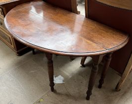 A mahogany gateleg dining table with drop flaps on ring turned legs and casters