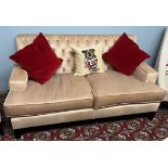 A modern two seater upholstered settee with button back upholstery on square tapering legs