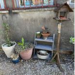 A bird table together with a steps and numerous garden plant pots