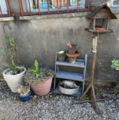 A bird table together with a steps and numerous garden plant pots