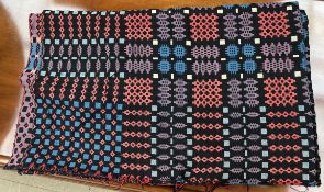 A Welsh blanket with a black ground and geometric patterns