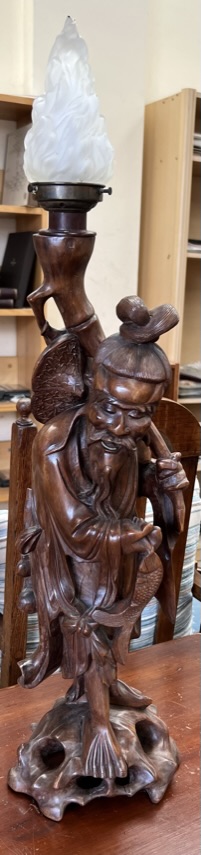 A Chinese hardwood figure of a deity holding a fish,