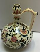 A Zsolnay Pecs Persian style jug decorated with flowers and leaves to a cream ground