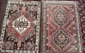 A pink ground rug with two central medallions, stylised flower heads and multiple guard stripes,
