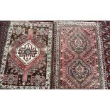 A pink ground rug with two central medallions, stylised flower heads and multiple guard stripes,