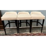 A set of three cream upholstered bar stools with ebonised square tapering legs