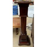 An Edwardian mahogany torchere with a crossbanded square top above a column on a stepped square