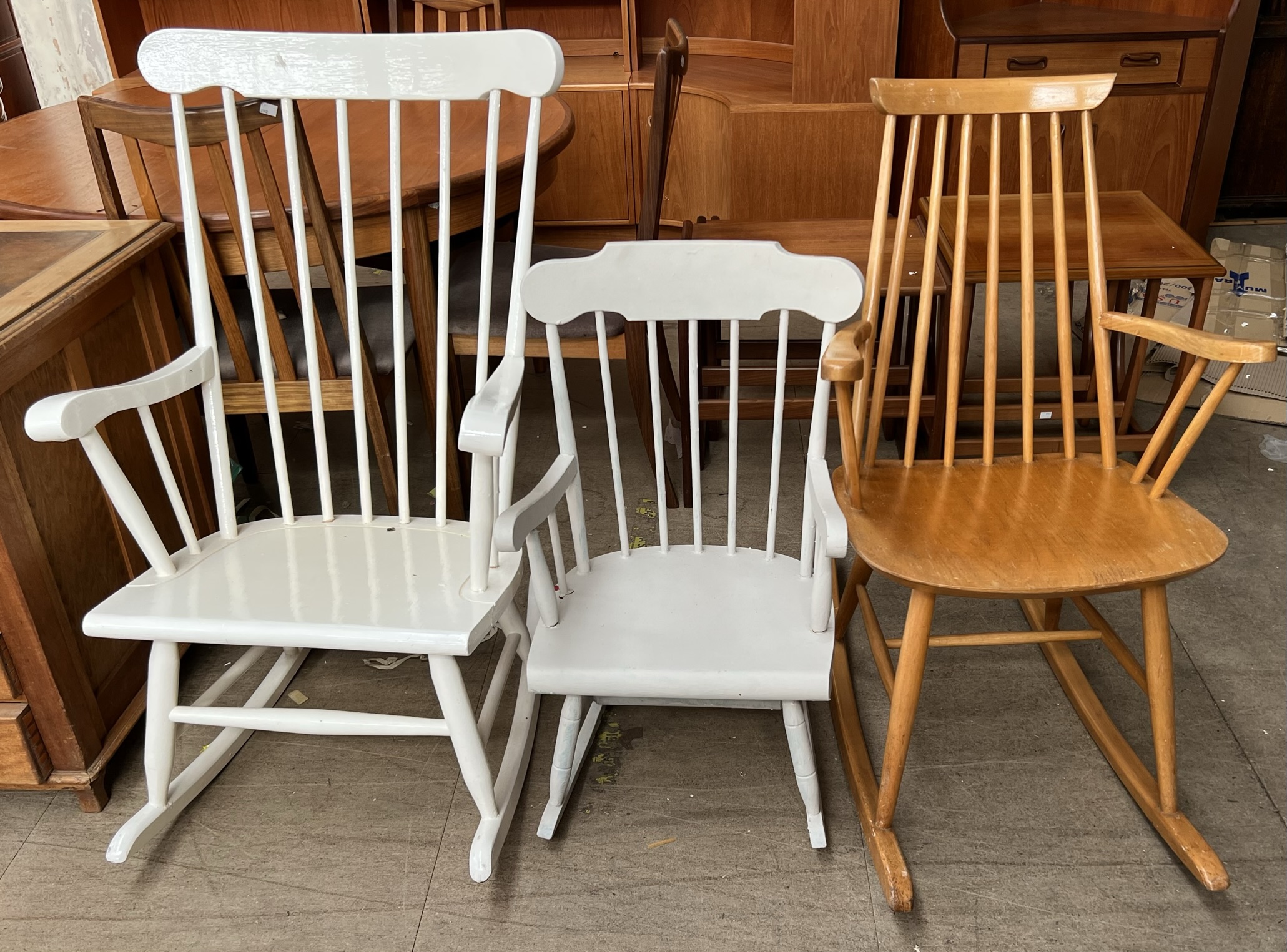 A white painted stick back rocking chair together with two other rocking chairs