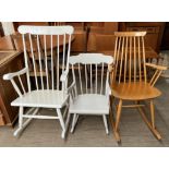 A white painted stick back rocking chair together with two other rocking chairs