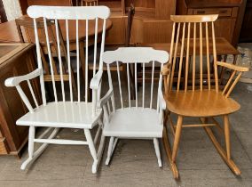 A white painted stick back rocking chair together with two other rocking chairs