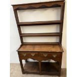 An 18th century South Wales style dresser with a moulded cornice above two shelves,