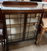 A 20th century mahogany display cabinet with glazed doors and sides on cabriole legs and claw and