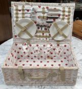 A Wicker hamper with a setting for four including plates,