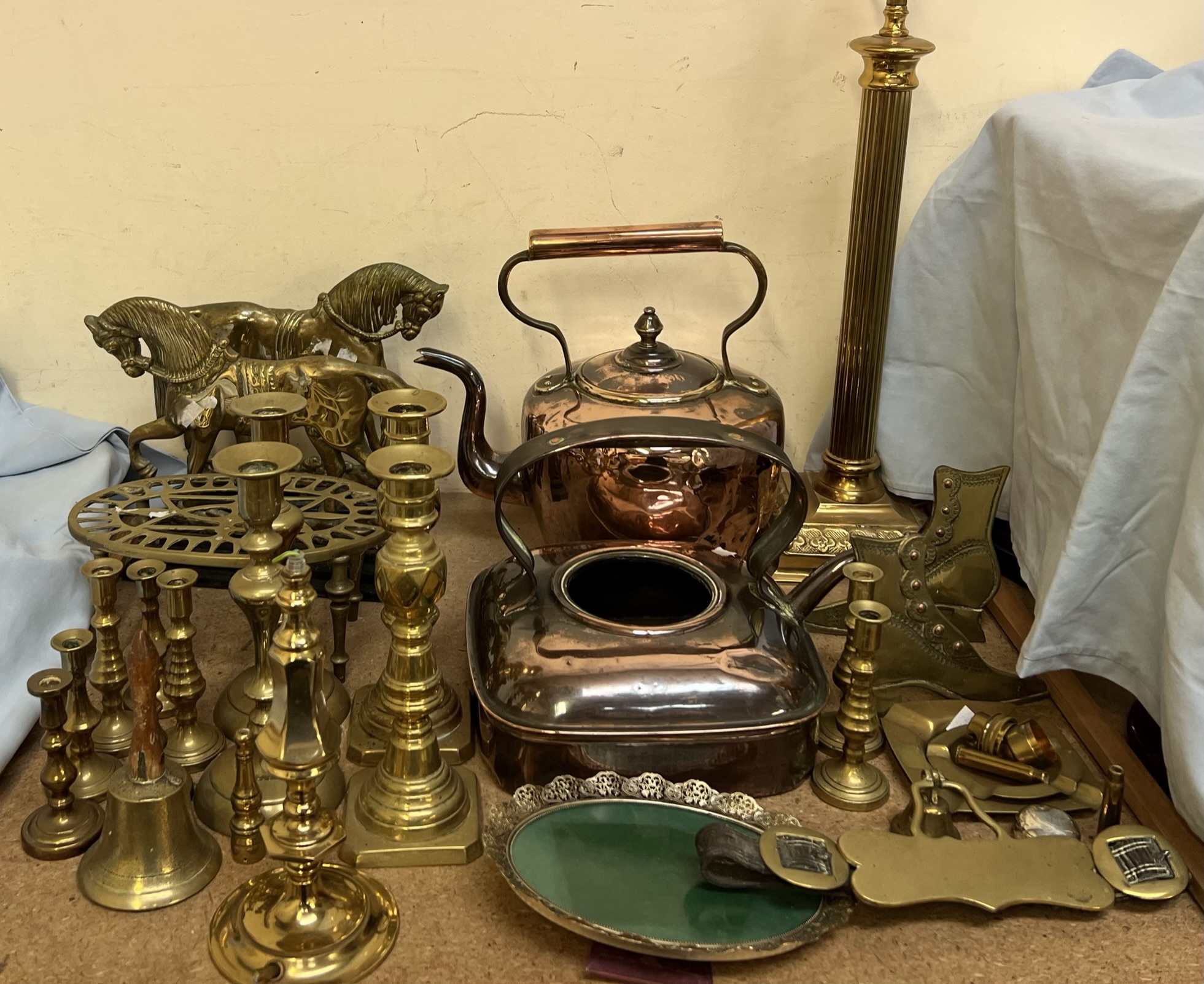 A pair of brass horse door stops together with various brass candlesticks, brass lamps,