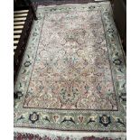 A room size rug, with a pink ground and green border, profusely decorated with flowers and leaves,