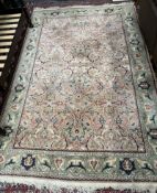 A room size rug, with a pink ground and green border, profusely decorated with flowers and leaves,