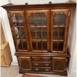 A modern wall unit with a moulded cornice above a glazed front and sides on a cupboard base