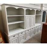 A modern wall unit / bookcase in three sections with cupboards, drawers and shelves,