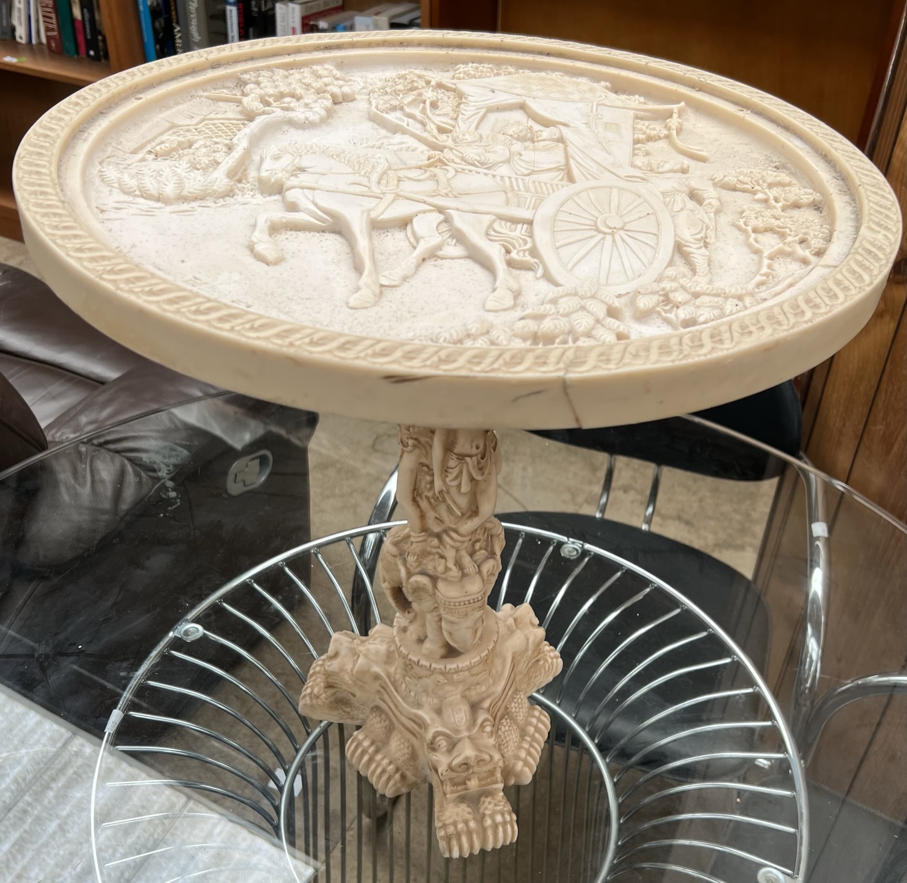 A simulated ivory wine table moulded with figures in a carriage,