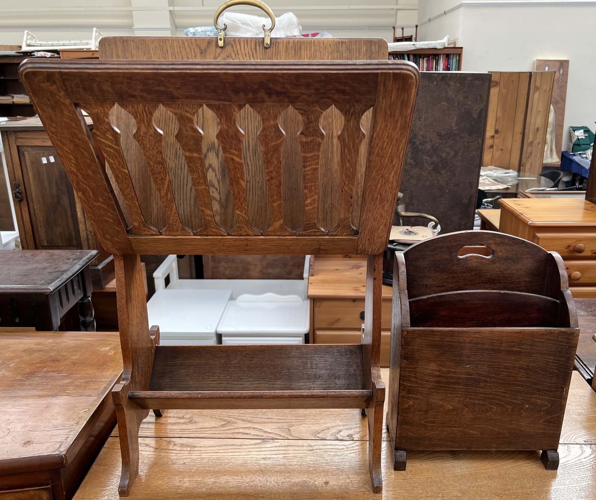 An oak magazine rack with folding pierced uprights and a brass carrying handle on shaped sides,