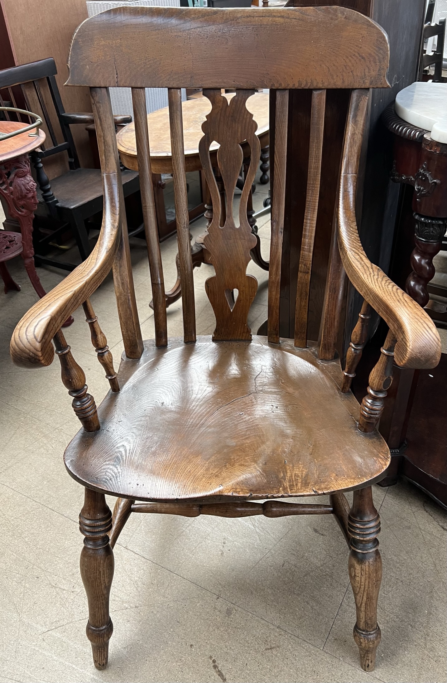 A 19th century kitchen elbow chair with a pierced vase splat and a solid seat on turned legs
