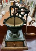 An early 20th century French Peugeot cast iron coffee grinder with a base drawer on a wooden base