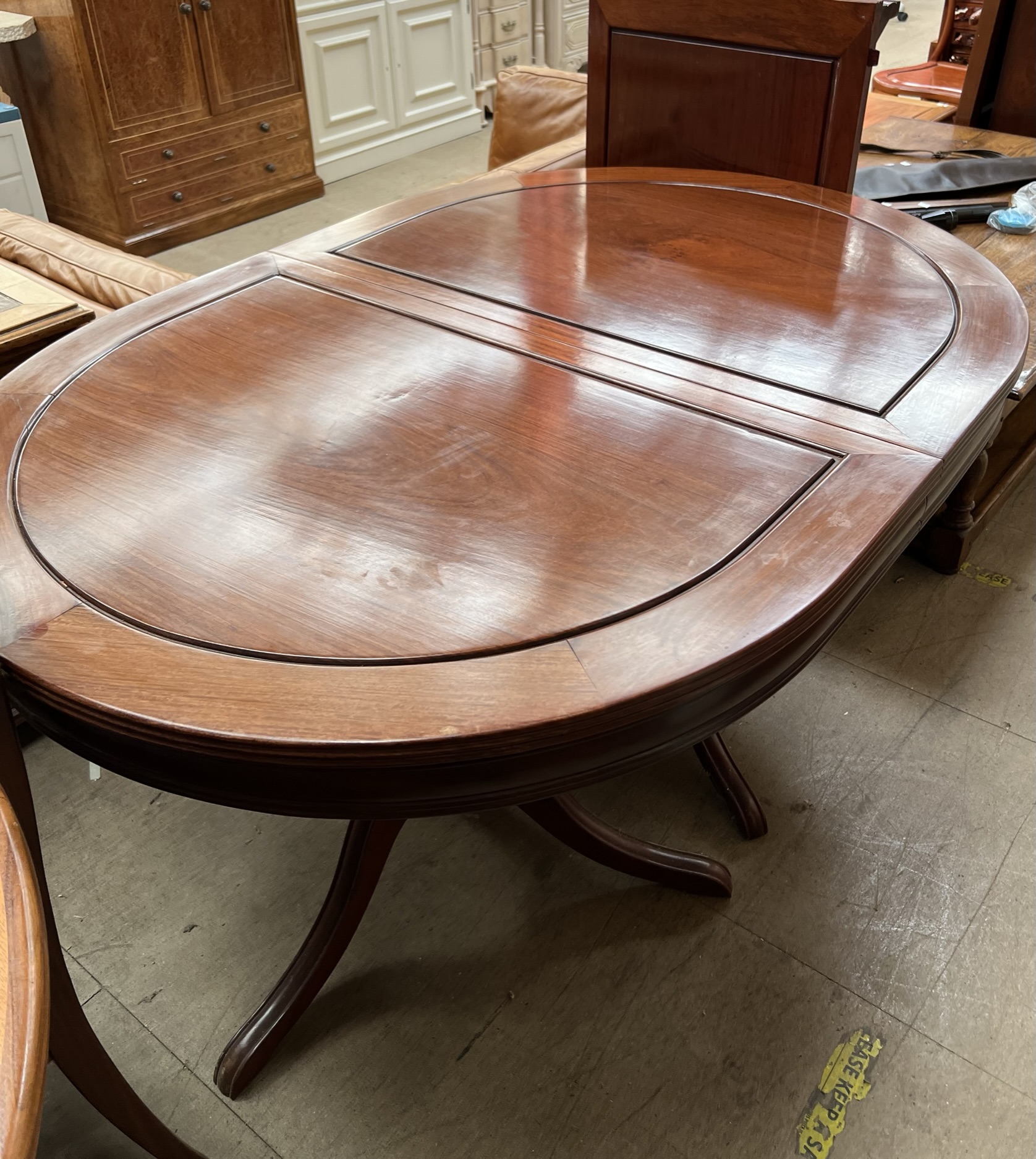 A Chinese hardwood extending dining table of oval form on twin pedestals with splayed legs together