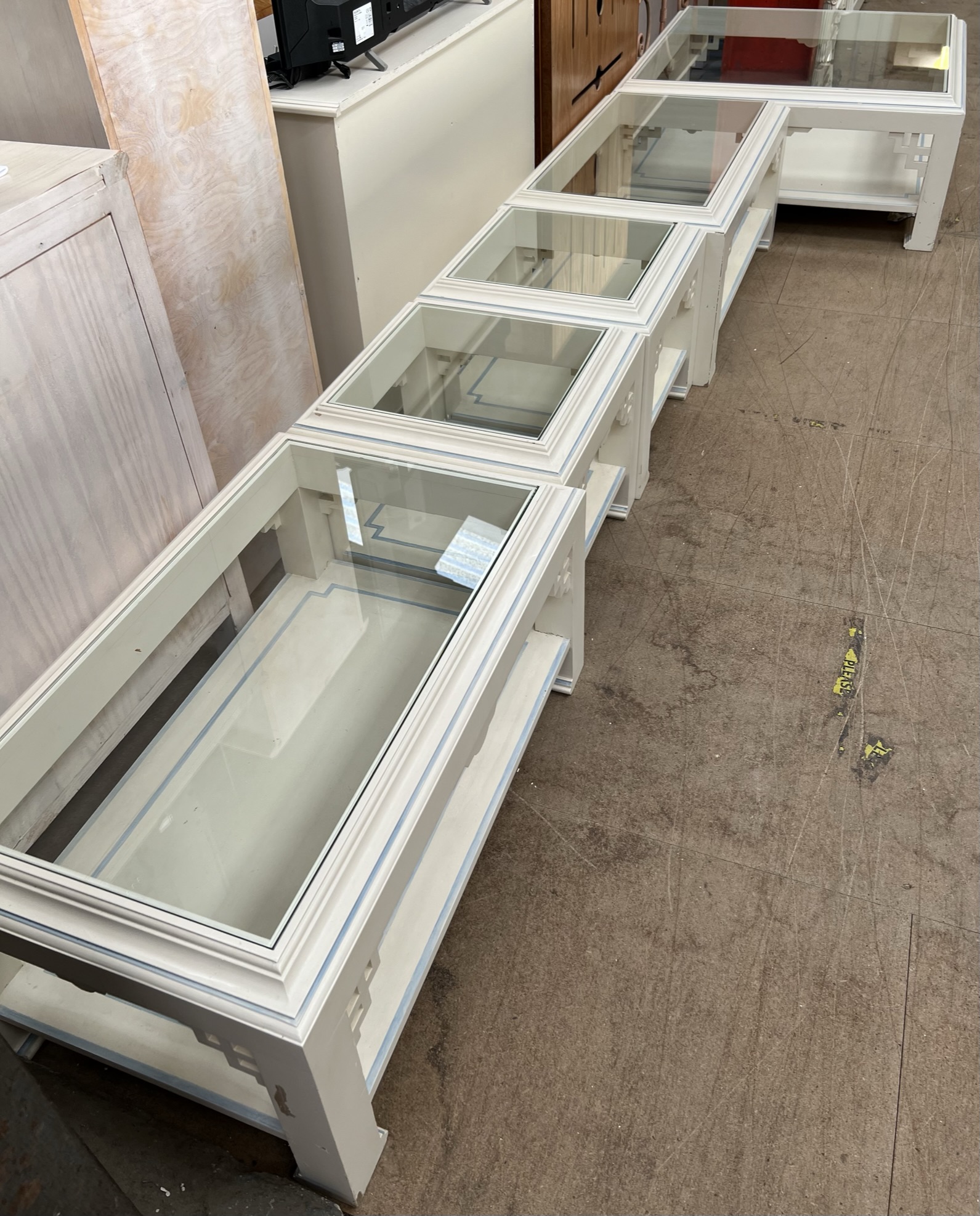 A set of five cream and blue painted glass topped coffee tables of varying sizes