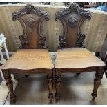 A pair of Victorian shield back hall chairs, with a carved cresting rail and sides,