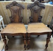 A pair of Victorian shield back hall chairs, with a carved cresting rail and sides,