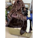 A fur coat together with a collection of fur stoles and a pad upholstered wicker stool