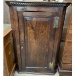 An 18th century hanging corner cabinet with a moulded dentil cornice above a single panelled door,