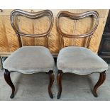 A pair of Victorian rosewood balloon back dining chairs with upholstered seats on shaped legs