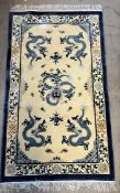 A Chinese rug with a cream ground decorated with dragons,