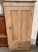 A continental pine wardrobe with a moulded cornice above a single door and two base drawers on