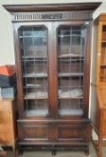 A 20th century oak bookcase, with a moulded cornice above a pair of leaded glass doors,